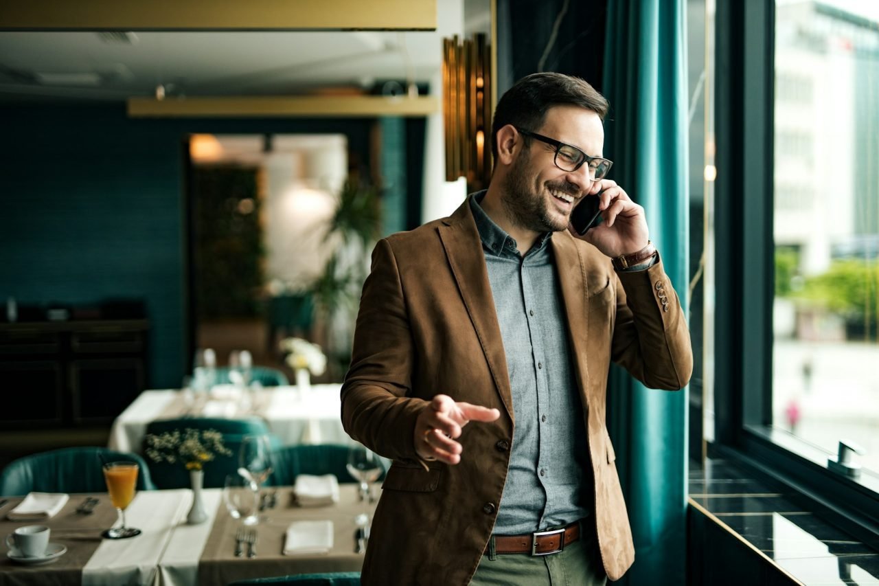 Hombre de negocios sonriendo en un restaurante mientras habla por telefono